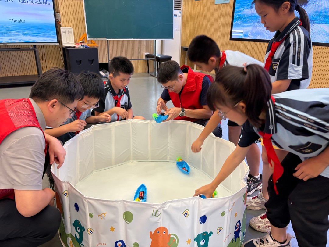 1778468496514720036.jpg 滚动图片7:志愿者和学生在水池中试验新组装的船舶模型(黎有福摄).jpg